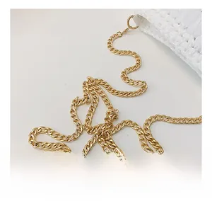 Close-up of high-quality light gold horseshoe curb chain with metal lobster clasp on white bag