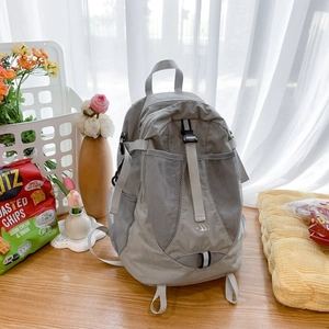 Stylish grey nylon backpack with mesh pocket on wooden table in natural light setting