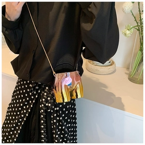 Macro detail of mini golden metallic crossbody bag with unique torso design and chain strap