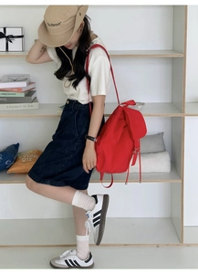 Lifestyle view of a large red nylon backpack with drawstring and flap on a female model