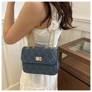 Detail of dark blue denim chain bag with classic diamond quilting and gold twist lock