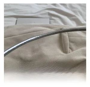 Macro shot of silver metal tube handle on beige corduroy fabric shoulder bag