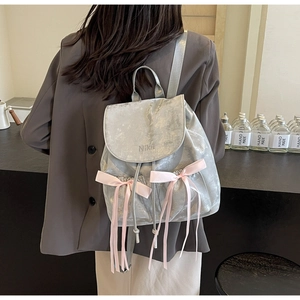 Detail of silver faux leather backpack featuring pink satin bows and Nika embroidery