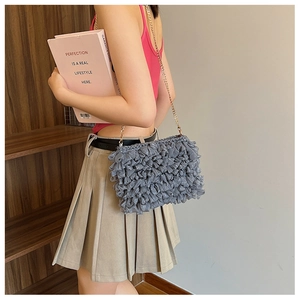 Close-up of grey pleated fabric crossbody bag featuring a golden metal chain strap