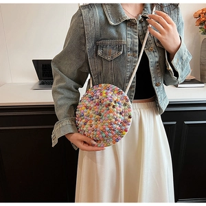 Dettaglio di una borsa a tracolla rotonda con perle colorate e una sottile tracolla bianca