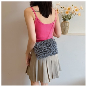 Detail view of gray pleated cloud crossbody bag with golden chain strap on model