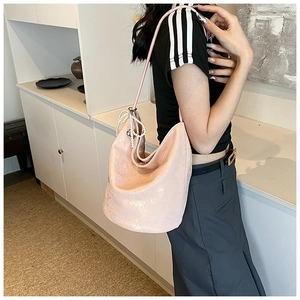 Detail of light pink metallic PU tote bag featuring decorative pearl charm on shoulder strap