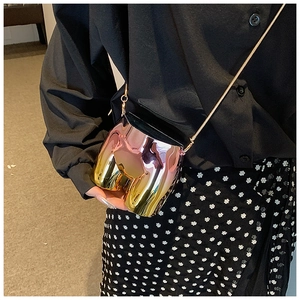 Detail of creative torso-shaped crossbody bag featuring gradient metallic plating and gold chain