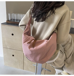 Close-up of pink crescent hobo bag featuring a brown ribbon bow on nylon fabric