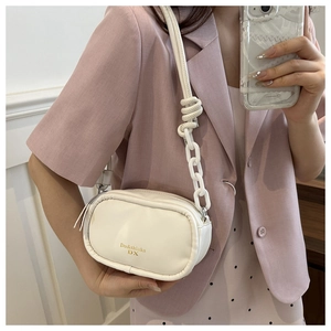 Detail of white PU leather crossbody bag with chain strap and gold logo lettering