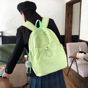 Dettaglio di uno zaino alla moda in nylon verde lime con un ciondolo a mostriciattolo