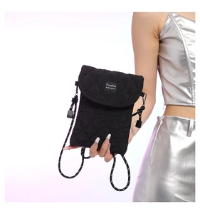 Close-up of black quilted nylon crossbody bag with diamond patterns and fashion label
