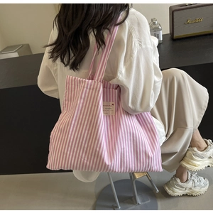 Detail of pink striped canvas tote bag with woven label and premium Marshall background