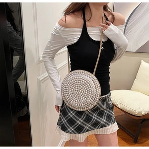 Dettaglio borsa a tracolla rotonda con eleganti decorazioni di perle e tracolla intrecciata