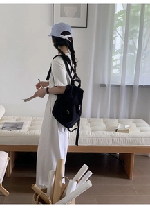 Modern black nylon backpack with flap closure shown in a minimalist summer lifestyle setting
