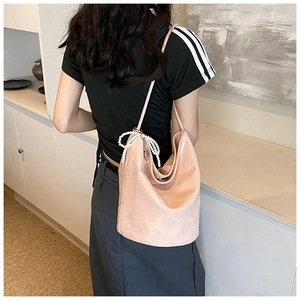 Detailed shot of pink PU tote bag with pearl bow pendant on shoulder of model