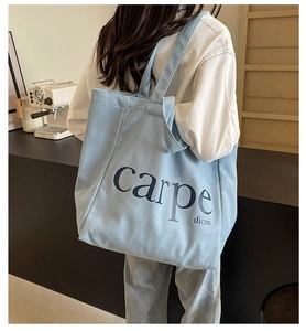 Close-up of light blue canvas tote bag with carpe dicnn lettering for daily casual use
