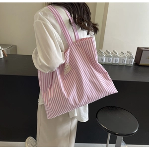 Lifestyle view of pink and white striped canvas tote bag with wide shoulder strap