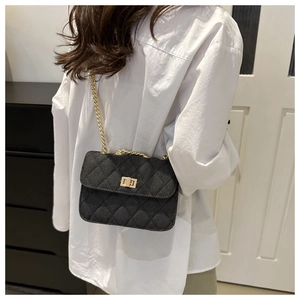 Detail of a black quilted crossbody bag with gold chain strap and metal lock closure