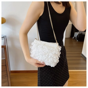 Detailed view of white ruffled crossbody bag with gold chain strap worn by a model