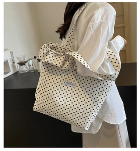 Detailed view of polka dot canvas tote bag with letter label and pleated edges