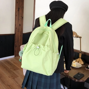 Dettaglio dello zaino in nylon impermeabile verde chiaro con tasca frontale a coulisse e charm