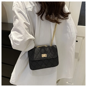 Close-up of black quilted denim crossbody bag featuring a gold twist lock and chain strap