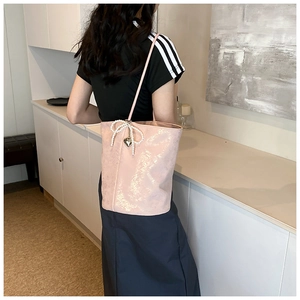 Pink PU leather shoulder bag with pearl bow and heart charm detail shown on model