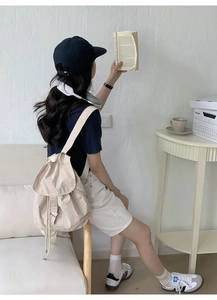Detailed view of cream nylon backpack with drawstring closure and silver metal buckle