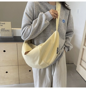 Detail view of a beige crescent crossbody bag with wide strap and minimalist design