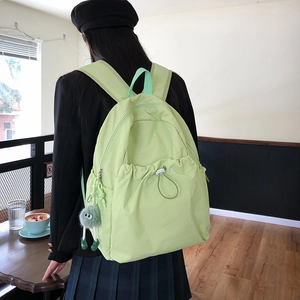 Dettaglio di uno zaino in nylon verde brillante con tasca a coulisse e un grazioso ciondolo