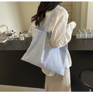 Detail of blue white striped canvas tote bag with woven tag and long shoulder straps