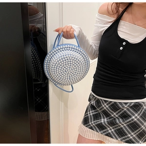Dettaglio della borsa rotonda in tessuto azzurro con decorazione di perle bianche