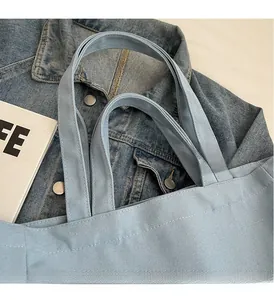 Close-up of light blue canvas tote bag showing reinforced handles and fine stitching details