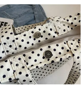Close-up of silver magnetic clasp and polka dot canvas fabric detail on a handbag
