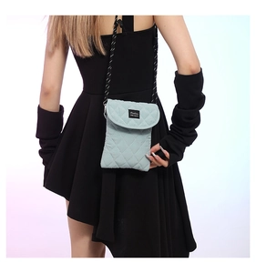 Close-up of light green quilted crossbody phone bag with black and white rope strap