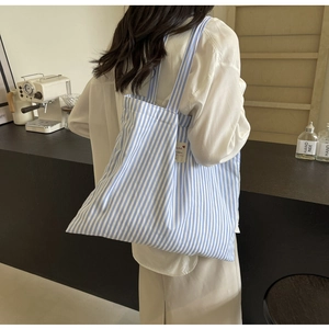 Detail showing vertical light blue and white stripes with a fabric side label on the tote bag
