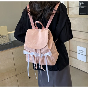 Pink ribbon backpack with Nika embroidery shown being worn in a cozy indoor setting