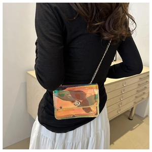 Close-up of a iridescent crossbody bag with golden chain strap on a model outfit