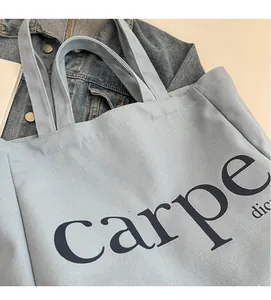 Close-up of light blue canvas tote bag with carpe diem print and soft denim background