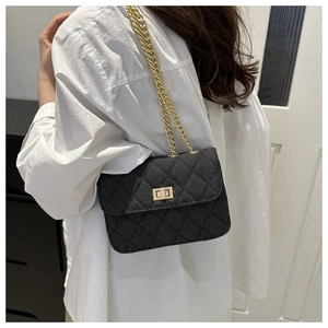 Detail of black quilted crossbody bag with gold chain strap and twist-lock clasp