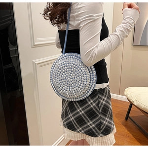 Dettaglio della borsa a tracolla celeste con file di perle decorative per un look elegante