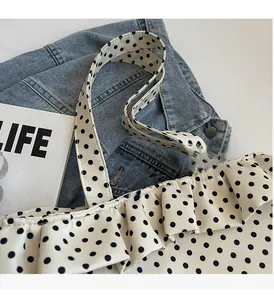 Close-up of fabric tote bag with black polka dots and ruffled edges on denim background