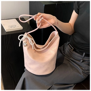 Close-up of pink PU leather bucket bag with pearl bow and metal heart pendant
