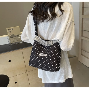 Detail of black polka dot canvas crossbody bag with lace trim and pearl accents