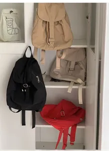 Detail view of nylon backpacks in khaki, black, cream, and red with drawstring closure
