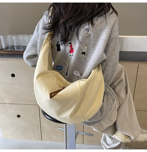 Close-up of a large yellow canvas crescent crossbody bag worn in a casual lifestyle setting