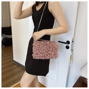 Detail of light pink pleated fabric crossbody bag with elegant gold chain strap