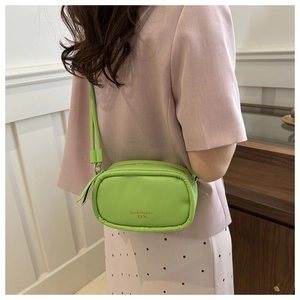 Detail of trendy neon green PU crossbody bag featuring logo print worn by model