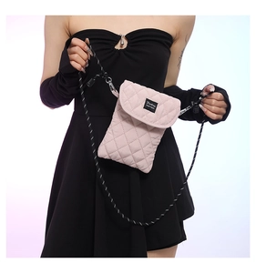 Detail of pink quilted crossbody bag with Fashion logo label and woven rope strap